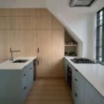 Kitchen under the sloped roofline at Haus A36 — multiplex with laneway suite in Playter Estates, Toronto by baukultur/ca.