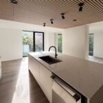 Home A kitchen sink and island at Haus L1 — multigenerational multiplex renovation in The Beaches, Toronto by baukultur/ca.